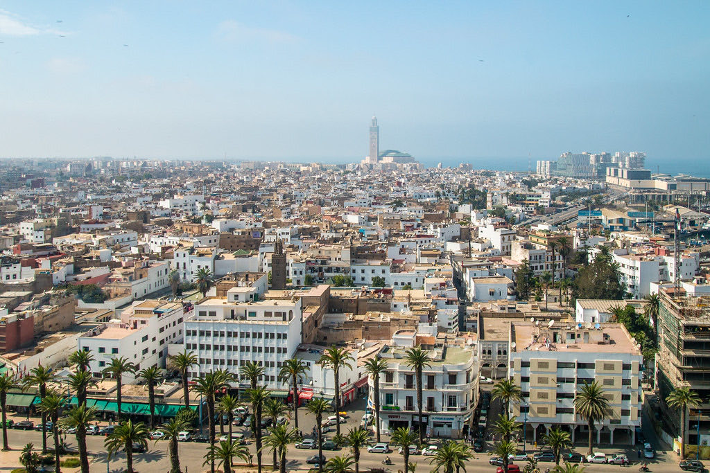 Vue sur Casablanca depuis les hauteurs, avec le minaret de la mosquée Hassan II et le boulevard bordé de palmiers